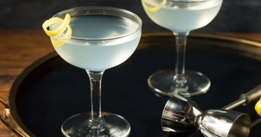 Un verre à cocktail transparent avec une boisson ambrée en cours de versement.