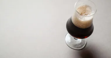Un verre à bière rempli d'un cocktail Irish Russian, avec une mousse beige au sommet.