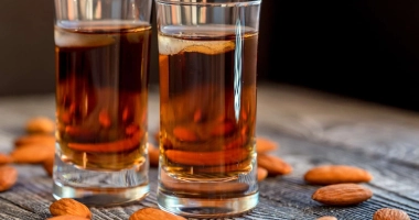 Trois bouteilles en verre remplies de liqueur amaretto maison, étiquetées avec du texte manuscrit.