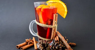 Verre de cocktail ambre avec glaçons et herbes aromatiques flottant à la surface.