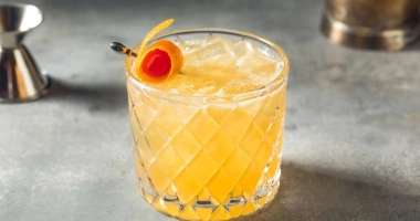 Verre de cocktail Amaretto Sour garni de cerises, posé sur un sous-verre.