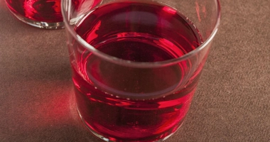 Verre rempli d'un cocktail rouge vif, décoré de motifs à pois blancs.
