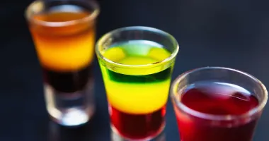Cocktail trois couleurs en couches vert, jaune et rouge dans un verre à shot.