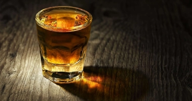 Un verre à shot rempli de liqueur ambrée sur une table en bois.