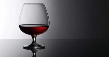 Verre à cocktail rempli d'une boisson rose translucide, avec des motifs élégants gravés sur le verre.