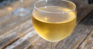 Un verre à pied bleu rempli d'un cocktail doré, typiquement un kir lorrain.