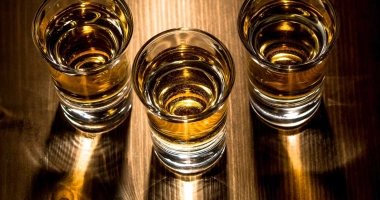 Trois verres à shot remplis d'un cocktail ambré, avec des gouttes de condensation sur les verres.