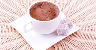 Tasse de chocolat chaud crémeux posé sur une soucoupe blanche.