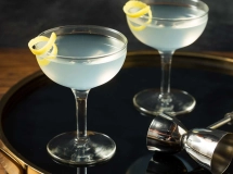 Un verre à cocktail transparent avec une boisson ambrée en cours de versement.