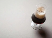Un verre à bière rempli d'un cocktail Irish Russian, avec une mousse beige au sommet.