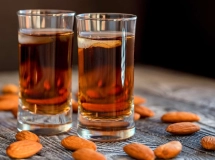 Trois bouteilles en verre remplies de liqueur amaretto maison, étiquetées avec du texte manuscrit.