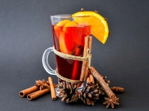 Verre de cocktail ambre avec glaçons et herbes aromatiques flottant à la surface.