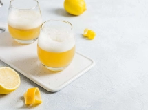 Un verre de Boston Sour garni d'un zeste de citron, avec une mousse blanche sur le dessus du cocktail.