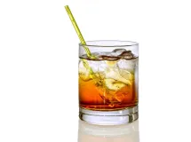 Un verre à whisky rempli de glaçons et d'un liquide ambré, posant sur une surface en ardoise, représentant un cocktail Godmother.