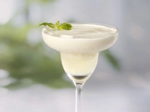 Un cocktail crémeux blanc dans un verre à martini sur fond flou avec une décoration en forme de fantôme.