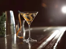 Verre à martini rempli de cocktail transparent avec des glaçons et une tranche de citron vert en garniture.