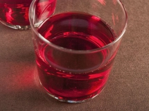 Verre rempli d'un cocktail rouge vif, décoré de motifs à pois blancs.