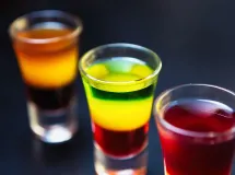 Cocktail trois couleurs en couches vert, jaune et rouge dans un verre à shot.
