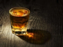 Un verre à shot rempli de liqueur ambrée sur une table en bois.