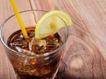 Verre de cocktail rempli de cola, glacé avec des glaçons, coiffé d'une tranche de citron.