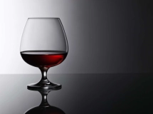 Verre à cocktail rempli d'une boisson rose translucide, avec des motifs élégants gravés sur le verre.