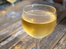 Un verre à pied bleu rempli d'un cocktail doré, typiquement un kir lorrain.