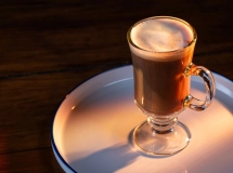 Cocktail Jamaican Coffee servi dans une tasse en verre avec une poignée, garni de crème fouettée et d'un bâtonnet de sucre.