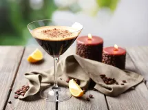 Un verre à martini contenant un cocktail espresso martini avec une mousse beige sur le dessus, décoré de trois grains de café.