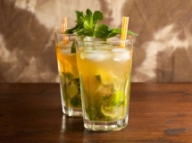 Un verre à cocktail Bacardi rempli de Mojito lorrain, avec des feuilles de menthe fraîche et des tranches de citron vert, surmonté d'une paille noire.