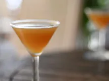 Cocktail ambré servi dans un verre à martini avec un sucre brun sur le bord.