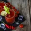 Verre de cocktail rempli de Tomato Tang, orné d'un quartier de citron vert et d'une paille rayée, avec un bord salé.