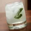Verre à whisky rempli de vodka fizz clair avec glaçons et feuilles de menthe fraîche.