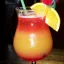 Verre à cocktail rempli d'un punch tropical aux couleurs dégradées du rouge au jaune, garni d'une tranche d'orange et agrémenté de décorations colorées.