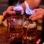 Deux chopes de bière contenant chacune une petite verrine enflammée placée à l'intérieur, tenues par des mains humaines.