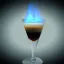 Un verre à cocktail rempli d'un mélange de liquides superposés, avec une flamme bleue flamboyante au sommet.