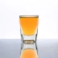 Un shot de cocktail jaune-orange vif dans un verre transparent sur fond blanc, représentant le cocktail Bubble Gum.