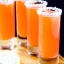 Trois cocktails Orange Crush servis dans des verres à bords salés, avec un fond de citron à l'avant.