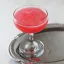 Verre à cocktail rempli d'une boisson rouge vif, sur un plateau en métal argenté.