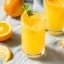 Verres de punch au rhum frais avec tranches d'orange, glaçons et garniture de menthe, entourés d'oranges entières et tranchées sur une nappe claire.